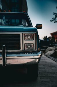 Front view of a vintage car parked outdoors, showcasing rugged elegance in Kuwait City at dusk.