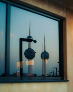 Captivating reflection of Kuwait Towers seen through a window during twilight.